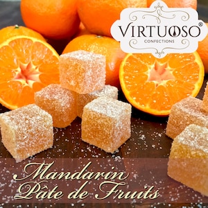 May include: Mandarin Pate de Fruits by Virtuoso Confections. Orange flavored jelly candies dusted with sugar crystals, arranged on a wooden surface with fresh mandarin oranges.