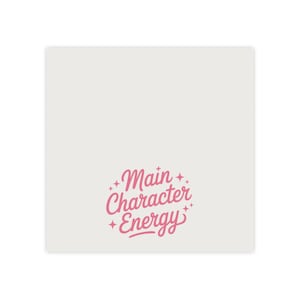 May include: A square, cream-coloured sticker featuring the pink text "Main Character Energy" in a cursive font, encircled by starbursts. The design is simple and modern, suitable for various applications.