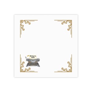 Può includere: Un blocco note quadrato bianco con disegni angolari dorati e un'illustrazione di macchina da scrivere vintage. Il blocco note presenta il testo "Writer's note" su un piccolo foglio. Il design è semplice ed elegante.