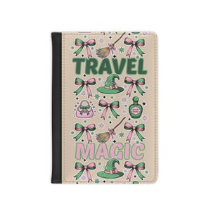 Puede incluir: Un portapasaporte beige con lomo negro. Tiene un patrón repetido de lazos verdes y rosas, sombreros de bruja, escobas y frascos de perfume. Las palabras "TRAVEL" y "MAGIC" están impresas en verde y rosa.