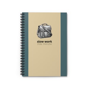 May include: A spiral-bound notebook with a tan cover and teal spine. The cover features a detailed black and white illustration of a satchel, with the words "slow work real results" printed below the image.