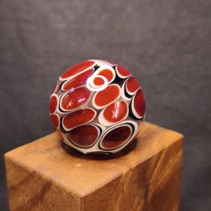 Red dots on clear handmade borosilicate glass marble.Dr Sawfish 2026.