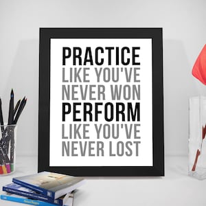 Op de afbeelding: Zwart-witte motiverende quote in een zwart frame. De quote luidt "Oefen alsof je nooit hebt gewonnen. Presteer alsof je nooit hebt verloren."
