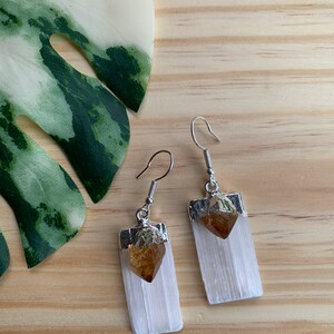 May include: A pair of silver earrings with white selenite crystal and a small golden citrine crystal at the top.
