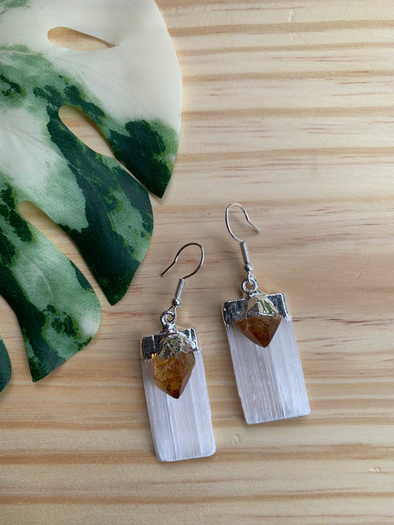 May include: A pair of silver earrings with white selenite crystal and a small golden citrine crystal at the top.