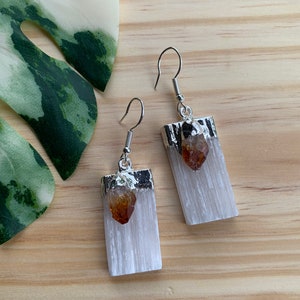 May include: A pair of silver earrings with white selenite stone and a small amber crystal accent.