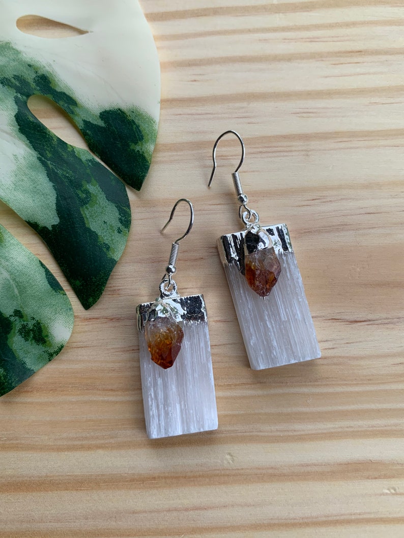 May include: A pair of silver earrings with white selenite stone and a small amber crystal accent.