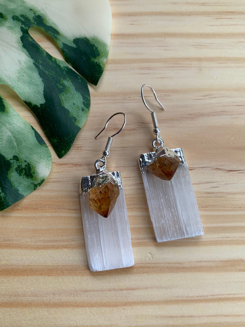 May include: A pair of silver earrings with a white selenite stone and a brown citrine crystal. The earrings are rectangular in shape and have a silver hook.