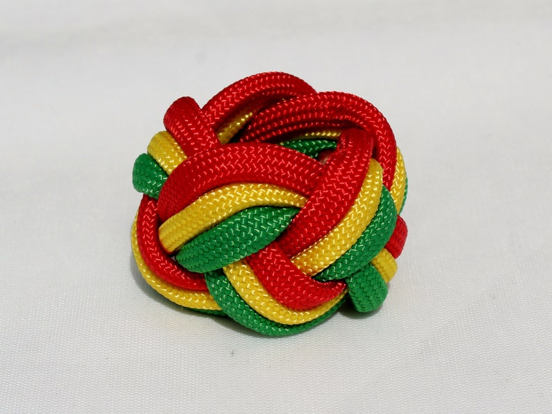 May include: A red, yellow, and green braided rope knot. The knot is tied in a complex pattern and is a popular decorative item.