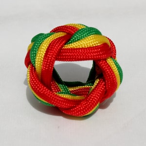 May include: A red, green, and yellow braided knot, also known as a Chinese button knot, is a decorative knot made from a single length of cord.