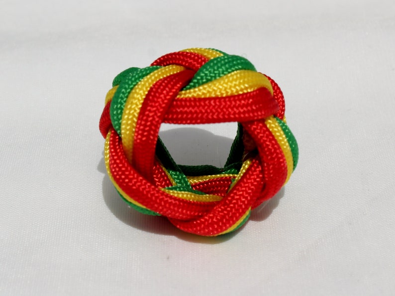 May include: A red, green, and yellow braided knot, also known as a Chinese button knot, is a decorative knot made from a single length of cord.