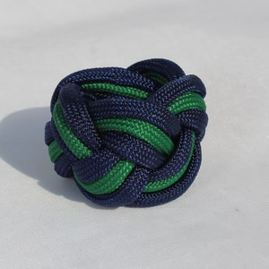 May include: A blue and green paracord knot, tied in a complex pattern.