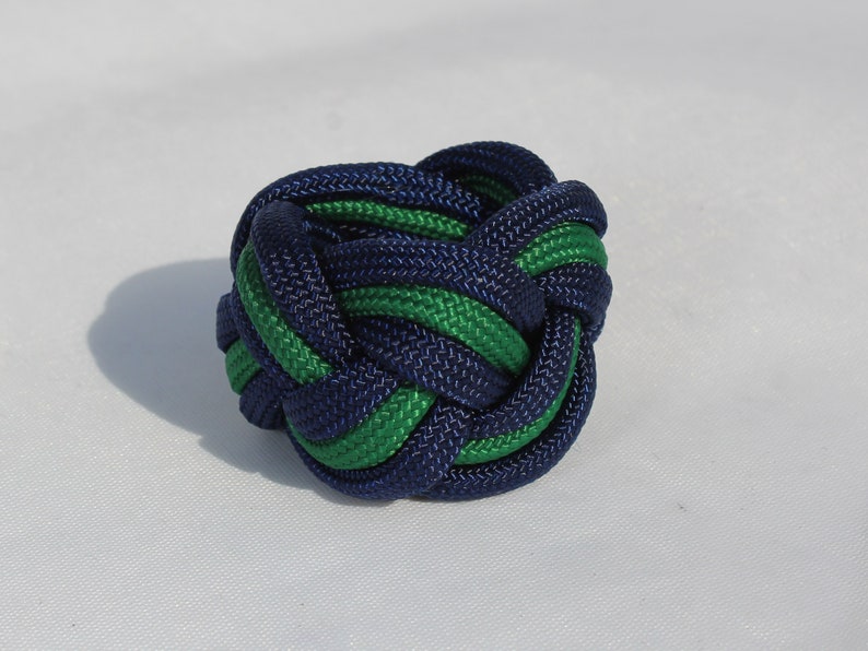 May include: A blue and green paracord knot, tied in a complex pattern.