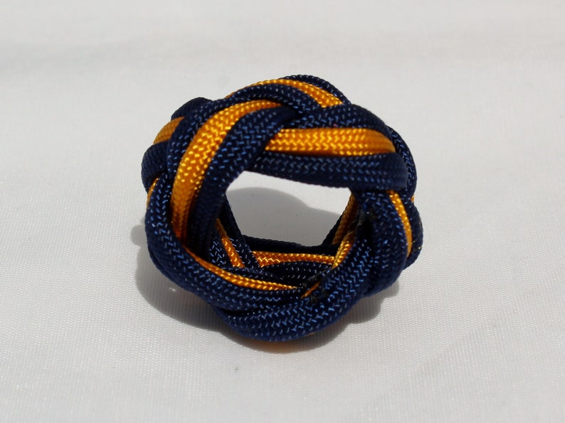 May include: A blue and gold braided knot, also known as a Chinese button knot, is a decorative knot that can be used as a keychain or a bracelet.