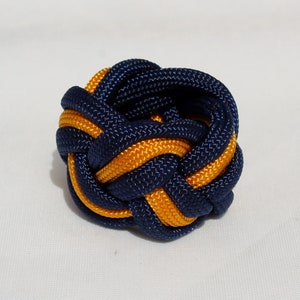 May include: A blue and gold braided rope knot, tied into a decorative ball shape.