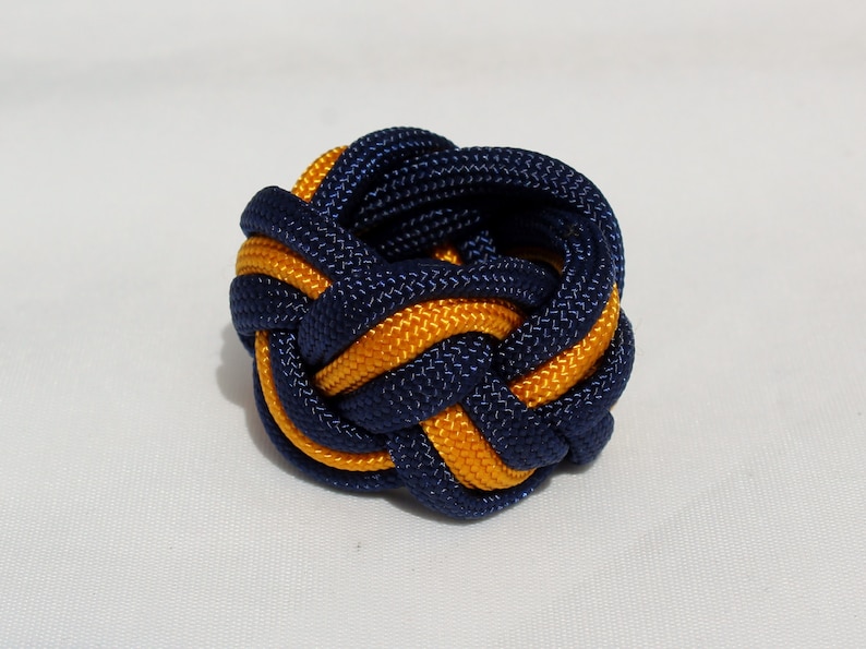 May include: A blue and gold braided rope knot, tied into a decorative ball shape.