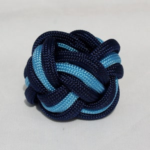 May include: A blue and light blue braided knot, tied in a complex pattern.