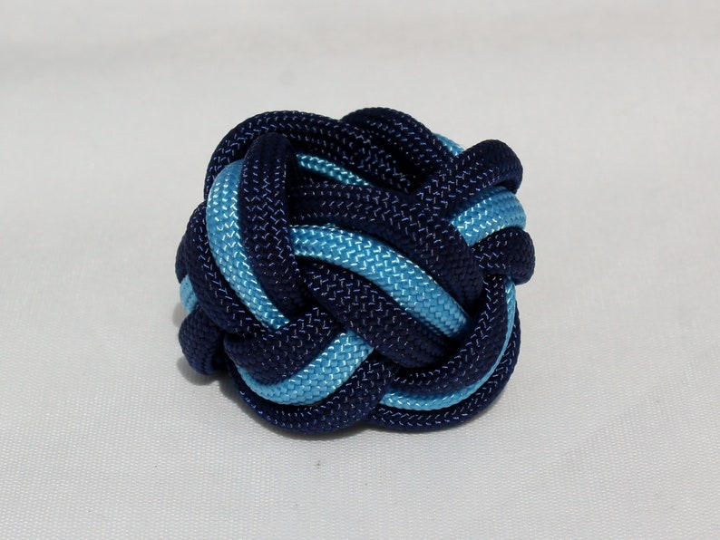 May include: A blue and light blue braided knot, tied in a complex pattern.
