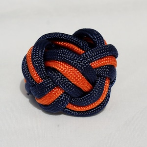 May include: A blue and orange braided knot, a decorative knot made from two colors of cord.