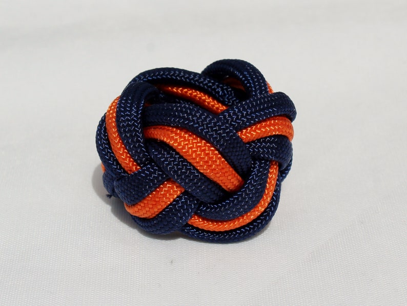 May include: A blue and orange braided knot, a decorative knot made from two colors of cord.