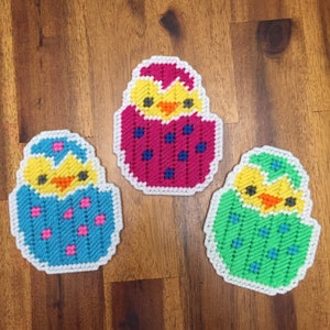 May include: Three felt Easter chick ornaments, each with a different colored egg. One is pink with blue polka dots, one is blue with pink polka dots, and one is green with blue polka dots.
