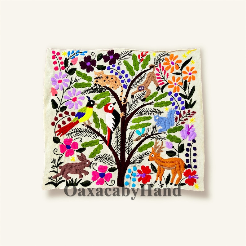 K&ouml;nnte beinhalten: Besticktes Textil mit einem Baum, auf dem bunte V&ouml;gel, ein Reh, ein Eichh&ouml;rnchen, ein Hase und ein Affe dargestellt sind. Der Baum ist von Blumen in Rosa, Lila und Orange umgeben. Der Text "OaxacabyHand" ist unten zu sehen.