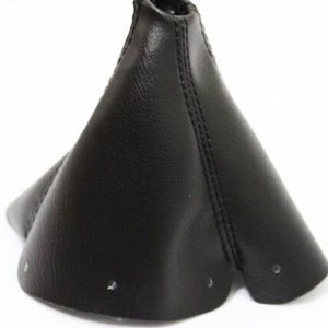 May include: Black leather gear shift boot cover. The cover is cone-shaped with a stitched seam down the center.