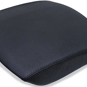May include: Black leather center console armrest cover with a stitched seam.