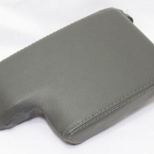 May include: Gray leather center console armrest cover with stitching.
