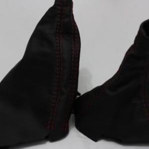May include: Two black leather gear shift boot covers with red stitching.
