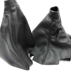May include: Two black leather gear shift boot covers. The covers are made of a textured leather and have a stitched seam down the center.