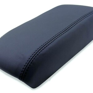 May include: A dark gray leather center console armrest cover with double stitching.