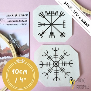 May include: Two white fabric patches with black embroidery of a compass rose design. The patches are 4 inches in diameter and are labeled "Stick, Sew + Wash". The patches are on a pink background with a wooden embroidery hoop and a package of water-soluble embroidery stickers.
