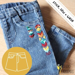 May include: Blue denim jeans with colorful embroidered geometric patterns on the side. The jeans are shown with a white outline of a pair of denim shorts. The text "STICK. SEW + WASH" is visible in the upper right corner of the image. The text "STUDIO KOOLMEES" is visible in the lower right corner of the image.