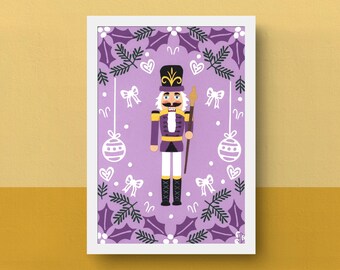 Könnte beinhalten: Gerahmter Druck mit einer Cartoon-Illustration eines Nussknacker-Soldaten. Der Nussknacker trägt eine lila Uniform mit goldenen Details und hält einen Stab. Der Hintergrund ist Lavendel mit Schleifen, Herzen und Ornamenten.