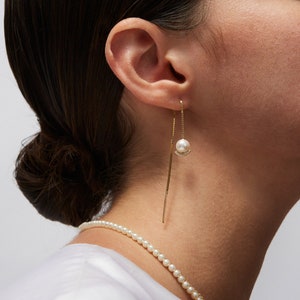 a close up of a person wearing a necklace and earrings