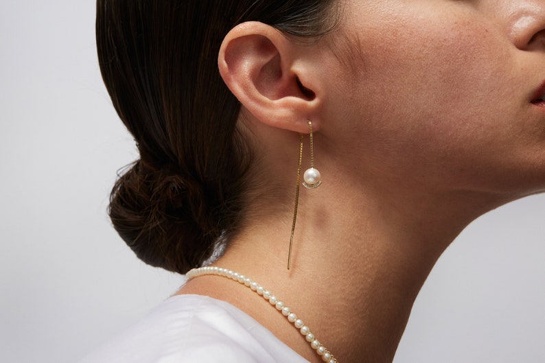 a close up of a person wearing a necklace and earrings