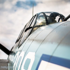 May include: Close-up of a vintage military aircraft, painted in a light blue and gray color scheme. The aircraft has a large, clear canopy and a machine gun mounted on the top. The aircraft is numbered "300" on the side.