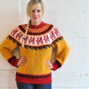 Könnte beinhalten: Ein gelber, roter und schwarzer Alpaka-Wollpullover mit geometrischem Muster. Der Pullover hat einen Rundhalsausschnitt und lange Ärmel.