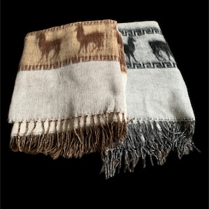 Pode incluir: Duas mantas de lã de alpaca com franjas. Uma manta é marrom com um design de lhama e a outra é cinza com um design de lhama.
