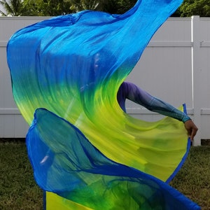 May include: A blue and yellow ombre fabric dance flag, also known as a worship flag, is being twirled by a person. The flag is made of a lightweight, flowing material.