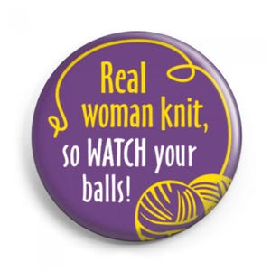 Könnte beinhalten: Ein runder, violetter Button mit gelbem Text und gelbem Rand. Der Text lautet "Real woman knit, so WATCH your balls!" mit zwei gelben Wollknäuel-Illustrationen.