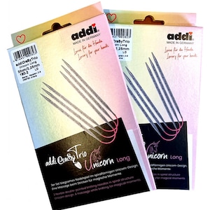Könnte beinhalten: Zwei Packungen addi CraSyTrio Unicorn Long Stricknadeln. Die Packungen sind rosa und weiß mit dem addi Logo und dem Text "Luxury for your hands". Die Nadeln sind silberfarben und haben ein Spiraldesign. Der Text auf den Packungen lautet "addi CraSyTrio Unicorn Long 30cm/2,25mm 180-2".