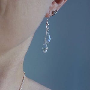 K&ouml;nnte beinhalten: Ein Paar silberne Ohrringe mit klaren, tropfenf&ouml;rmigen Kristallen.