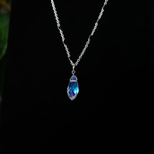 May include: A silver chain necklace with a blue iridescent crystal pendant.