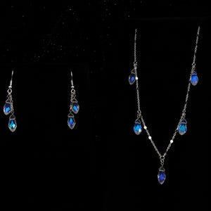 K&ouml;nnte beinhalten: Eine silberne Halskette und passende Ohrringe mit blauen, schillernden Kristall-Tropfenanh&auml;ngern.