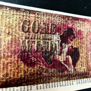May include: A vintage-style collage featuring a couple embracing, with the words "Gone With The Wind" superimposed over them. The background is a mix of brown, red, and gold tones, with text from a book visible.