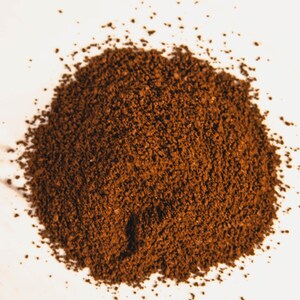 Peut inclure: Gros plan sur un tas de caf&eacute; moulu finement, de couleur brun fonc&eacute;. Les grains de caf&eacute; sont dens&eacute;ment tass&eacute;s, cr&eacute;ant une surface textur&eacute;e. L'image est bien &eacute;clair&eacute;e, soulignant la couleur riche et la consistance fine du caf&eacute;.