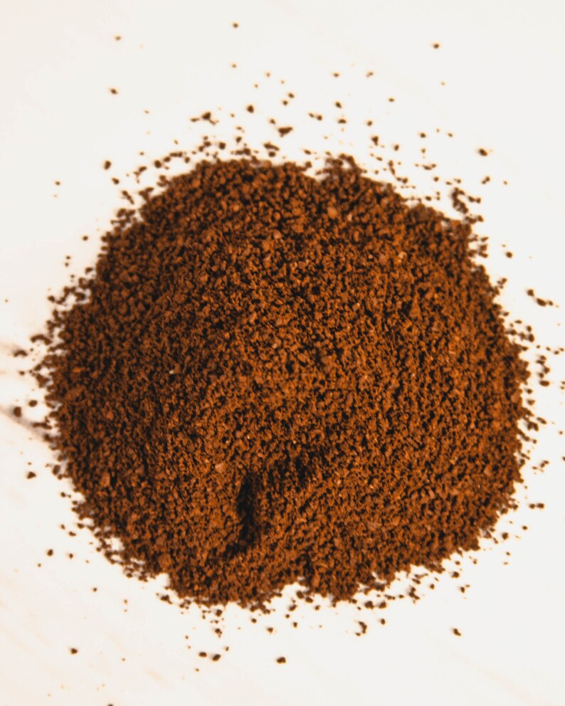 Peut inclure: Gros plan sur un tas de caf&eacute; moulu finement, de couleur brun fonc&eacute;. Les grains de caf&eacute; sont dens&eacute;ment tass&eacute;s, cr&eacute;ant une surface textur&eacute;e. L'image est bien &eacute;clair&eacute;e, soulignant la couleur riche et la consistance fine du caf&eacute;.