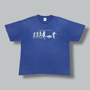 May include: A blue t-shirt with a crew neck featuring a white graphic of the evolution of a zombie man. The graphic shows a series of stick figures transforming into a zombie. The text "The Evolution of Zombie Man" is above the graphic.